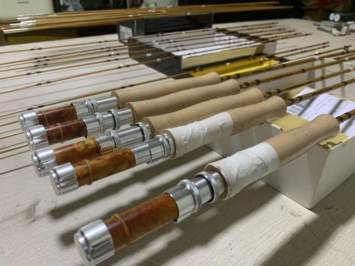Rows of bamboo fly rods with cork grips and wooden reel seats in the workshop.