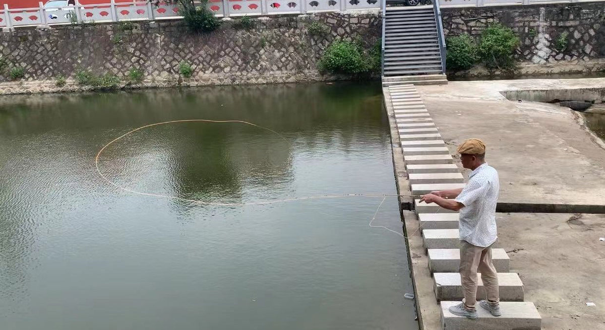 Angler casting a fly rod from stone steps beside the water.