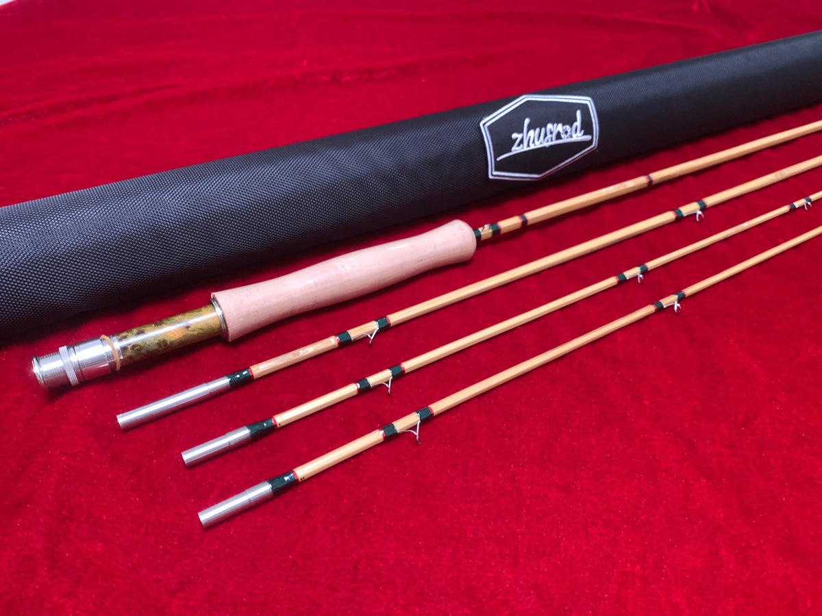 Bamboo fly rod sections and a ZHUSROD cloth rod bag on red fabric.