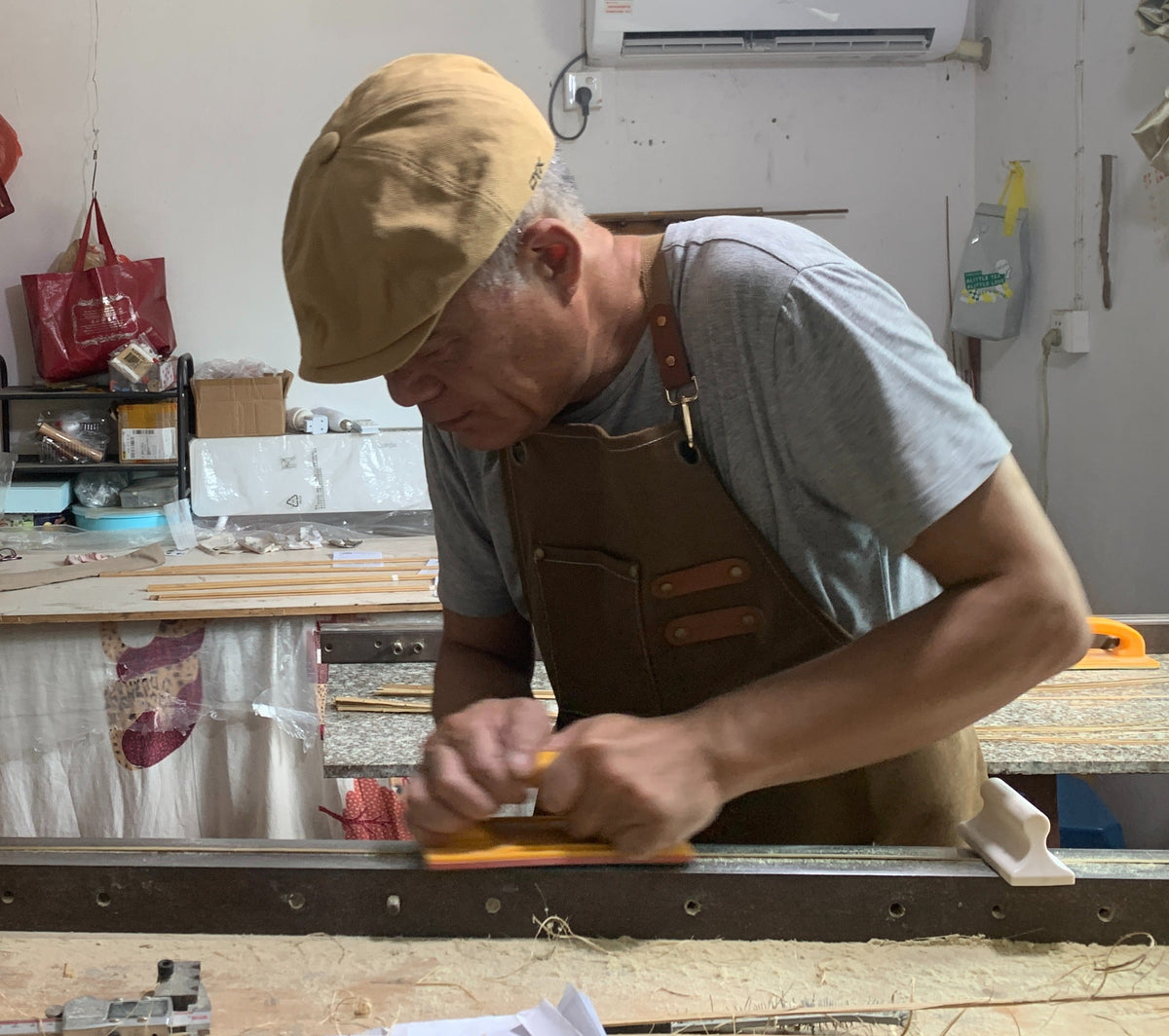Rod maker hand-planing a bamboo strip at a workshop bench.