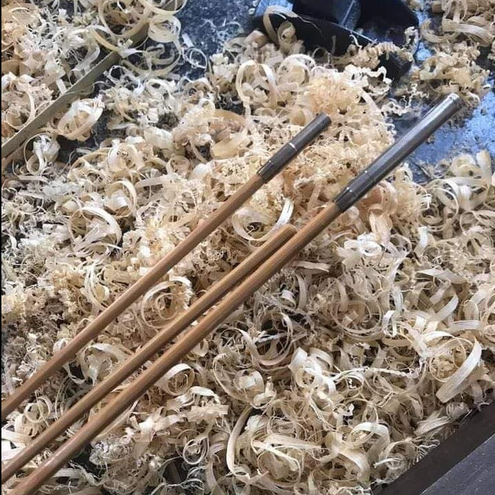 Bamboo rod sections and hand tools laid among curled cane shavings.