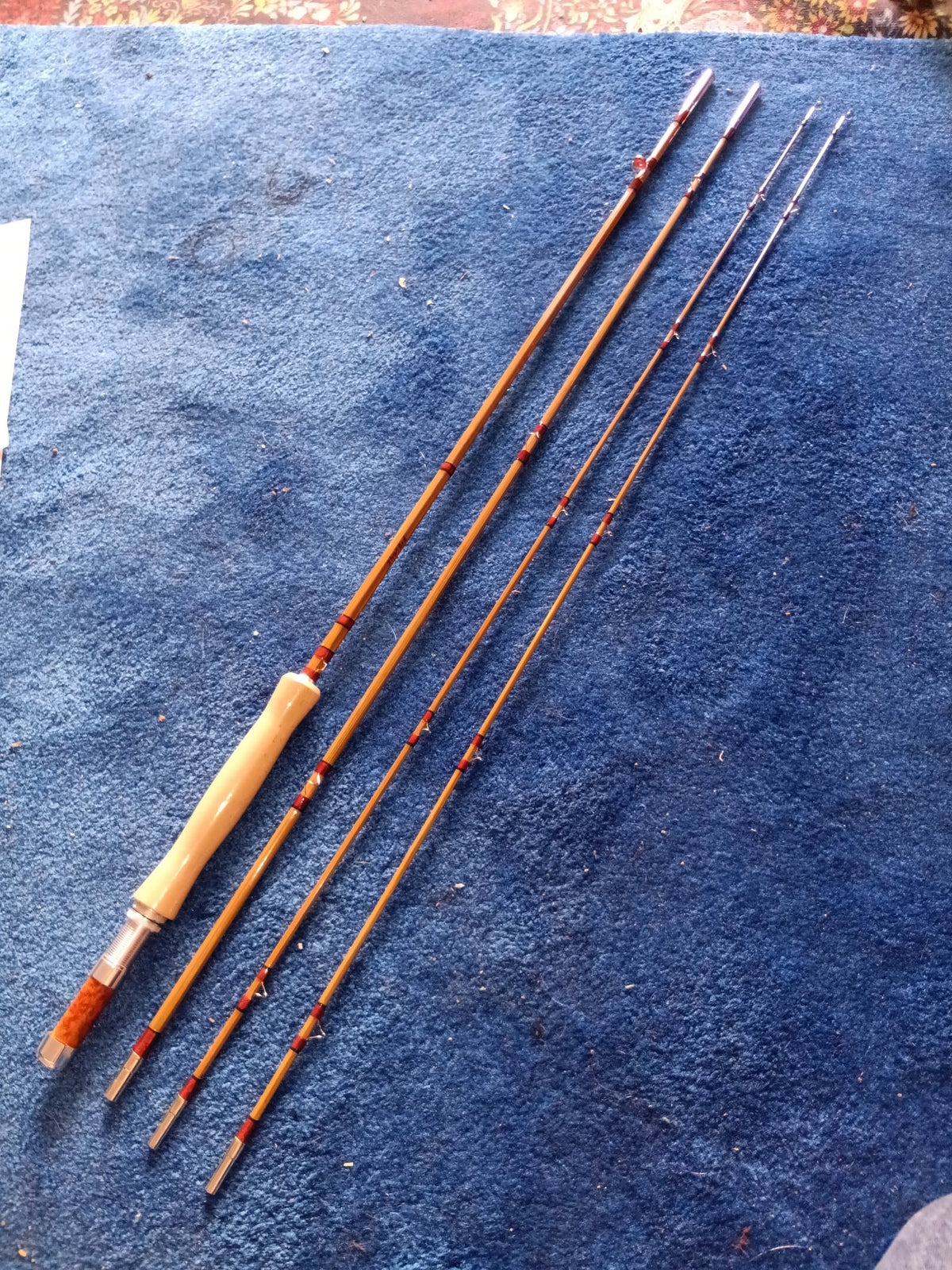 Bamboo fly rod sections with a cork grip and additional tips on blue fabric.